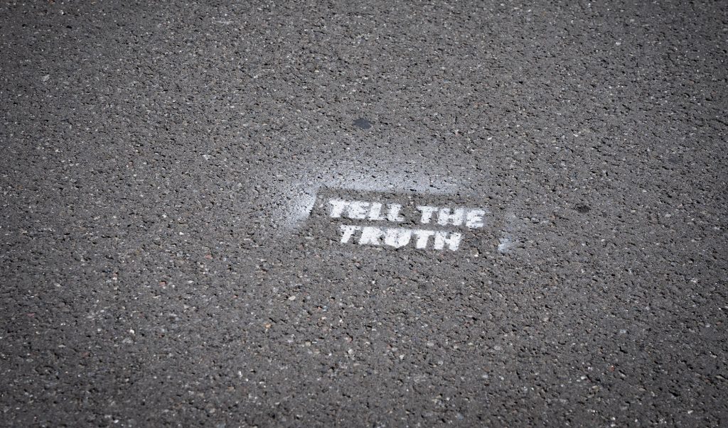 „Tell the truth” scris pe asfalt